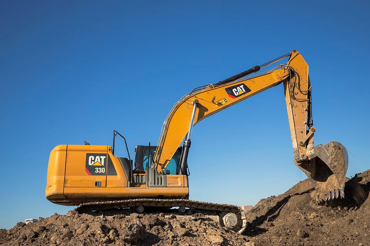 Caterpillar 330 excavator on a dirt pile, illustrating heavy equipment brand comparison for resale value analysis