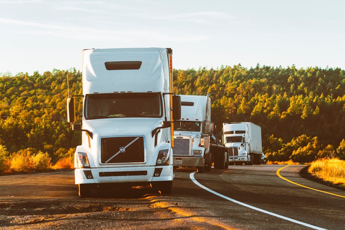 Heavy construction equipment being loaded onto a flatbed trailer for transport across the United States