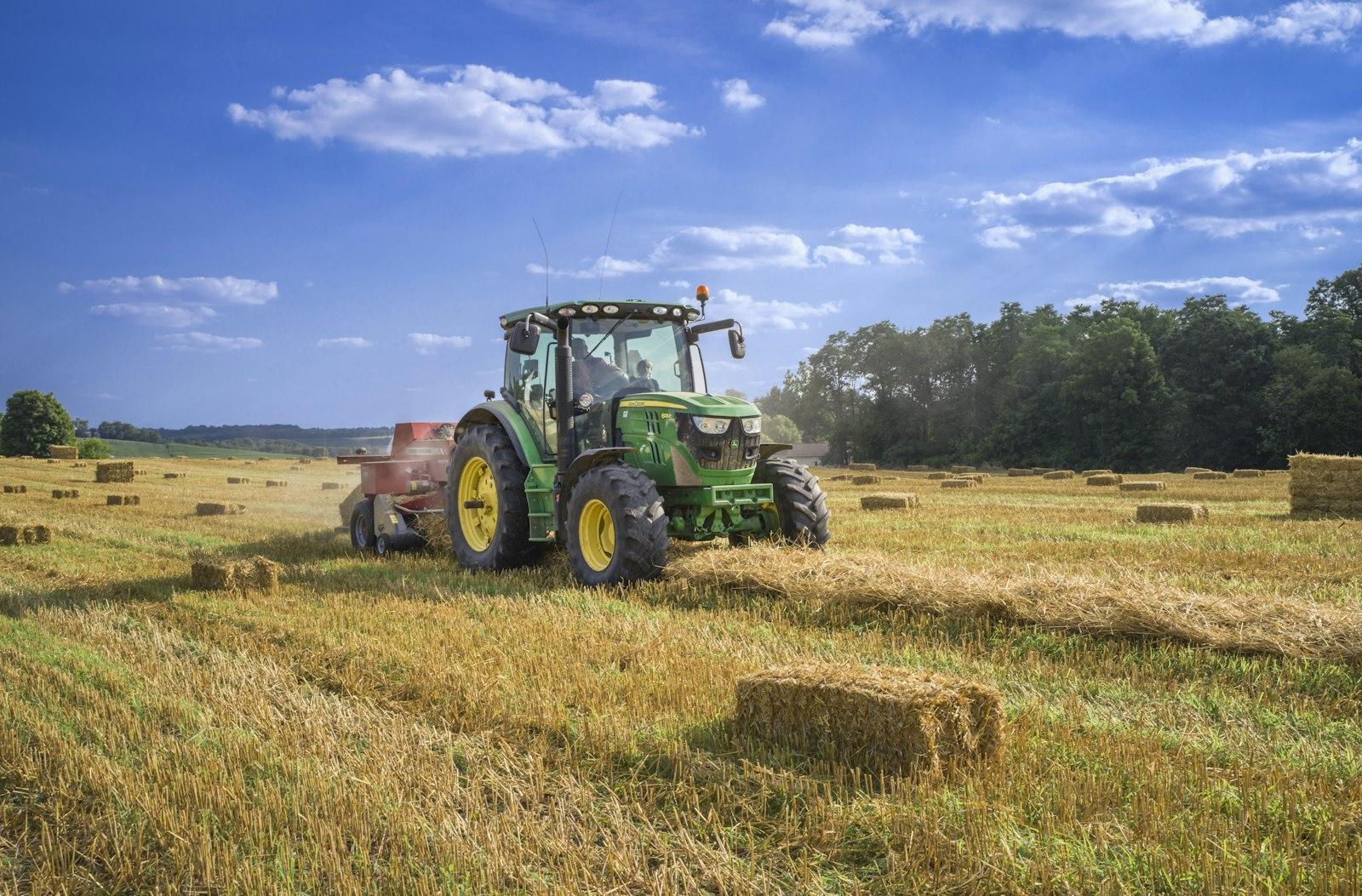 Green utility tractor working in a field, illustrating the difference between engine horsepower and PTO horsepower for tractor implement work
