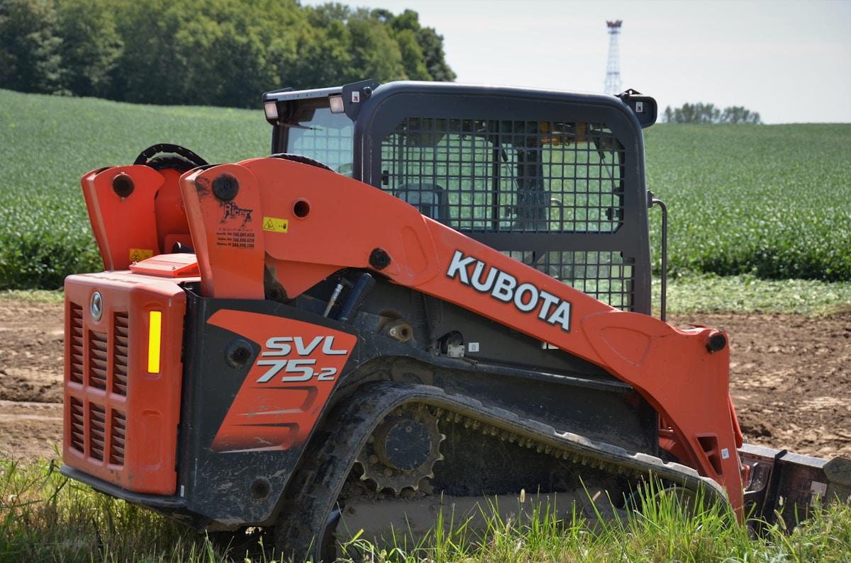 Orange compact tractor in a green field, illustrating Kubota vs John Deere vs Mahindra compact tractor brand comparison